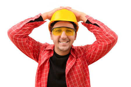 Male worker or engineer in a yellow helmet smiling looking at the camera on a white background....