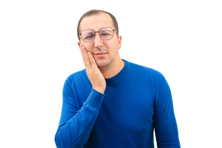 Young man suffering from toothache touching cheek on white backgroundの写真素材