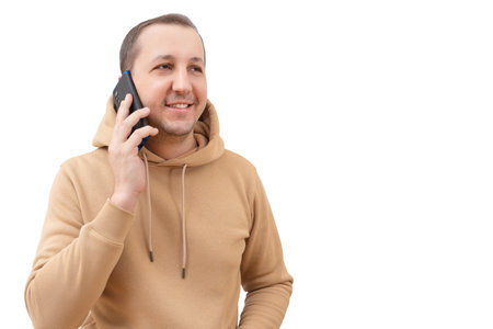 Young happy man in hoodie using smartphone on white background in studio.の写真素材