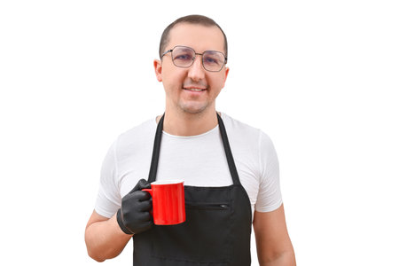 Portrait of a man in an apron with a cup in his hands looking at the camera against a white background.の写真素材
