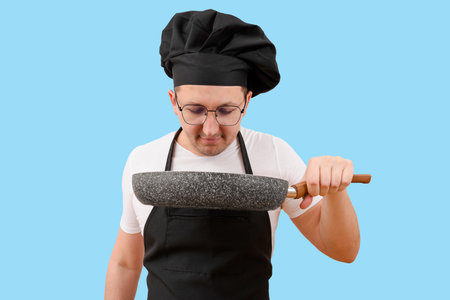 A cook with a frying pan in his hand on a blue background. Cooking conceptの写真素材