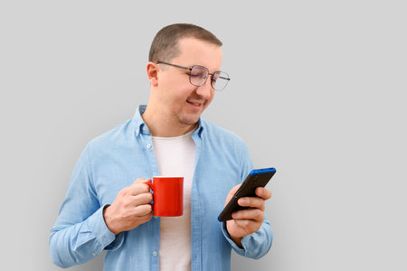 Business man with a cup and a phone in his hands on a gray background.の写真素材