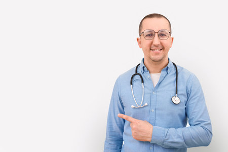 Happy doctor with stethoscope pointing with finger on white background.の写真素材