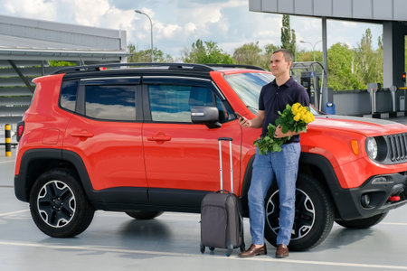 A young man with a suitcase stands near the car. Travel concept, car rental, business tripの写真素材