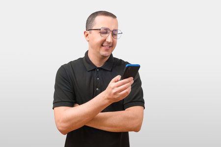 Smiling young man holding a mobile phone in his hand, isolated on a gray background. People lifestyle conceptの写真素材