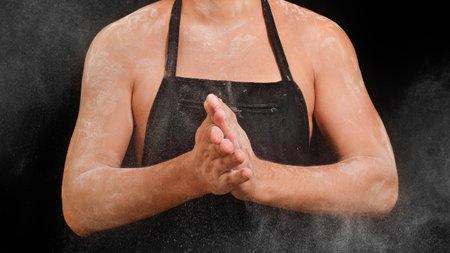 Chef clapping hands with flour on black background.の写真素材