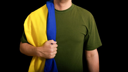 The military man holds the national flag of the Country on a black background.の写真素材
