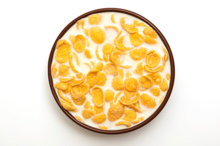Cornflakes in a bowl with milk on a white background, top view