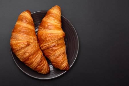 Croissants in a plate on a black background. View from above. French pastriesの写真素材