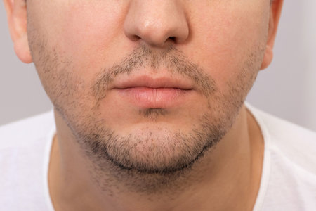 Close-up of the face of a young man with a beard. Young bearded man on a gray background.