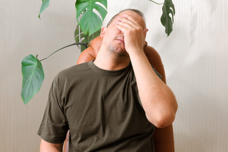Nervous man suffering from depression and headache sitting alone at home.の写真素材