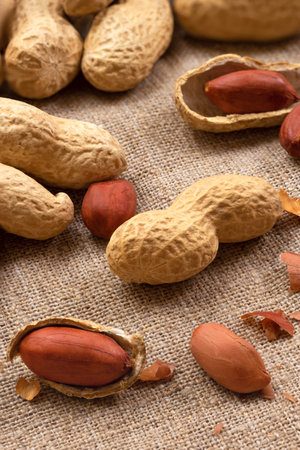 Food background of peanuts in shell on burlap. Heap of roasted nuts