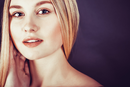 Beautiful young blonde woman with long straight hair on a dark backgroundの写真素材