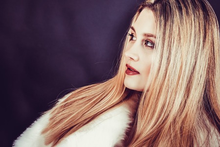 Beautiful young blonde woman with long straight hair on a dark background