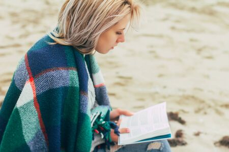 A girl reads a book on the beachの写真素材