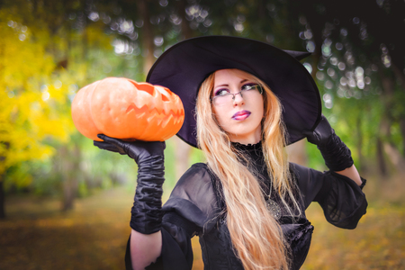 Happy halloween witch girl keeps orange pumpkinの写真素材