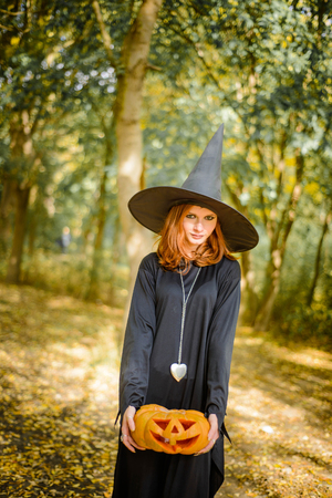 Happy halloween witch girl keeps orange pumpkinの写真素材