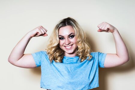 Blonde woman on a light background shows a biceps. Close-upの写真素材