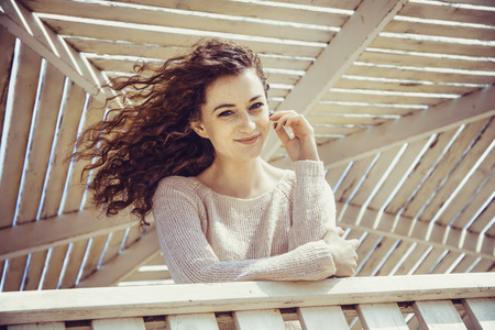 Curly girl smiling with happiness in a sunny alcove close-upの写真素材