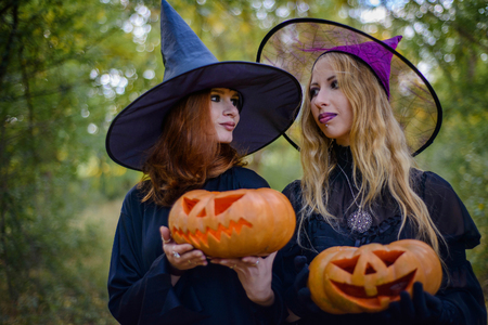 Happy Halloween. Two witches standing and holding orange pumpkinの写真素材