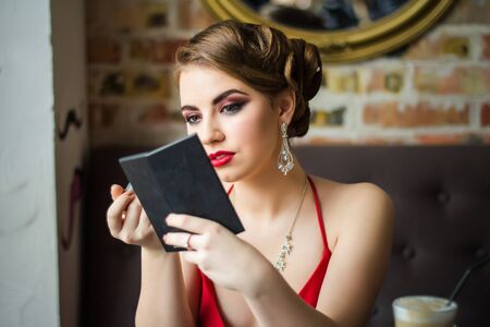 Retro image. Girl paints her lips red lipstick. Close-up