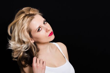 Woman with blonde curls and red lipstick on a dark background closeupの写真素材
