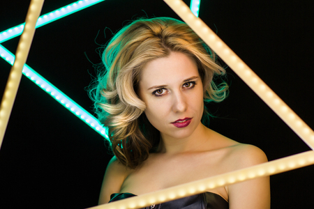 Woman with blond curls laying close-up on a dark backgroundの写真素材