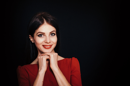 A beautiful woman with black straight hair and blue eyes in a burgundy dress on a dark background. Close-up. Space for textの写真素材