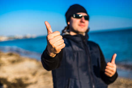 The man is showing a thumbs up on a blurred background. Close-upの写真素材