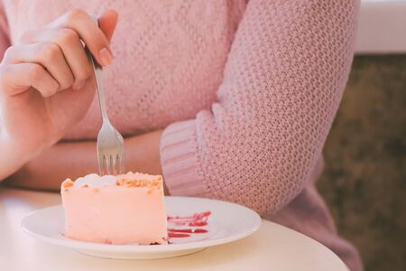Woman at the table eating a fork cake. Close-up