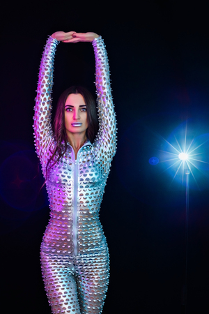 A woman with long hair in a silver suit against a dark backgroundの写真素材