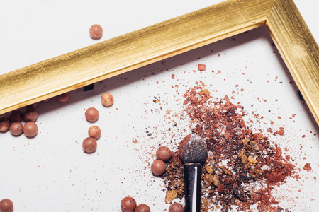 Cosmetics. Scattered shadows, applicator, balls of blush in a golden frame.の写真素材