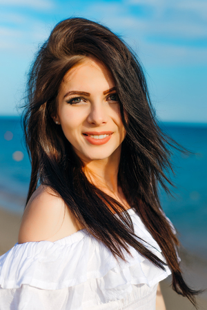 Woman in hat and white dress on the background of the seaの写真素材