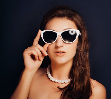 Woman on a dark background close-up with glasses. Pin-up styleの写真素材