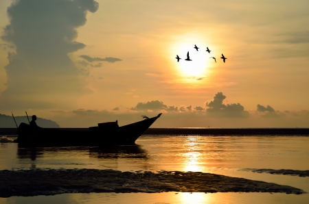 Fishing Boat at Sunrise with bird flying aroundの写真素材