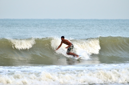 KUANTAN, MALAYSIA - 6 NOV 2013 - Surfer rides the back side of a wave during monsoon at Teluk...