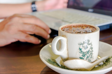 Cup of hot chocolate with computer. Working concept. Soft focus, selective focus (focus on buble), and shallow depth of field (big aperture)の写真素材