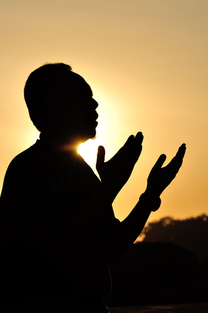 Silhouette of a Muslim praying over golden sunsetの写真素材