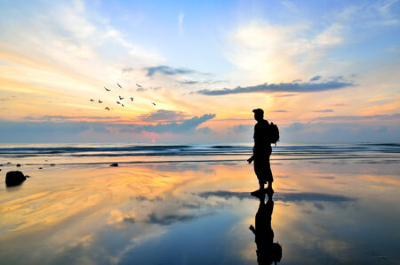 Silhouette of a photographer looking to the birds flying when sun rising upの写真素材