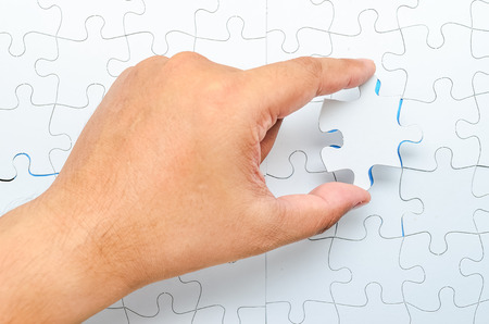 Person fitting the last puzzle piece.Concept image of building and button upの写真素材