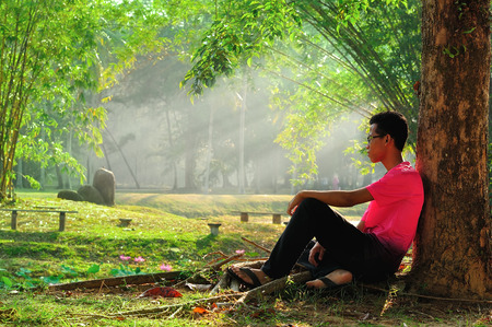 Man sitting alone under treeの写真素材