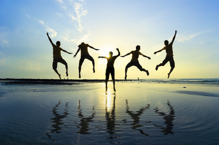 Silhouette of friends jumping over sun rising up