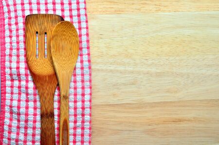 Wood background with copyspace bordered by a red and white country cloth with wooden kitchen utensils lying on top of itの写真素材