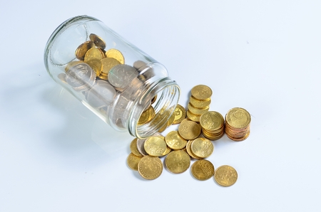 Coins spilling out of a glass bottleの写真素材