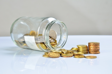 Coins spilling out of a glass bottle