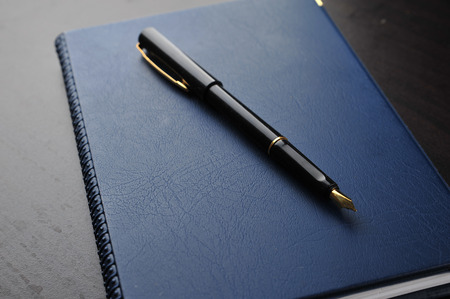 Notebook with fountain pen on wooden tableの写真素材