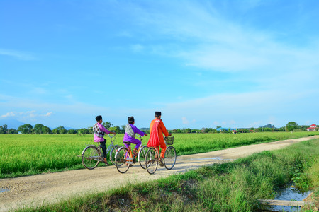 happy young local boy riding old bicycle at paddy fieldの写真素材