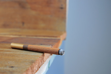 Burning handmade luxury Cuban cigar on an old wooden background with copyspaceの写真素材