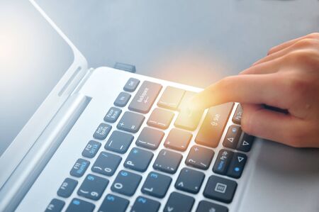Woman hand touching laptop computer keyboard - Focus on the keyboard