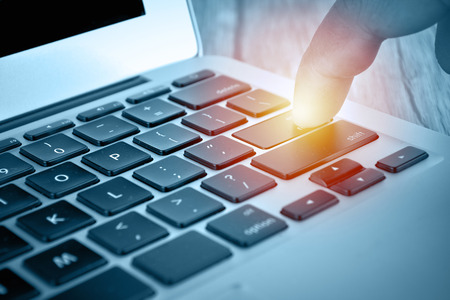 Hand touching laptop computer keyboard - Focus on the keyboardの写真素材